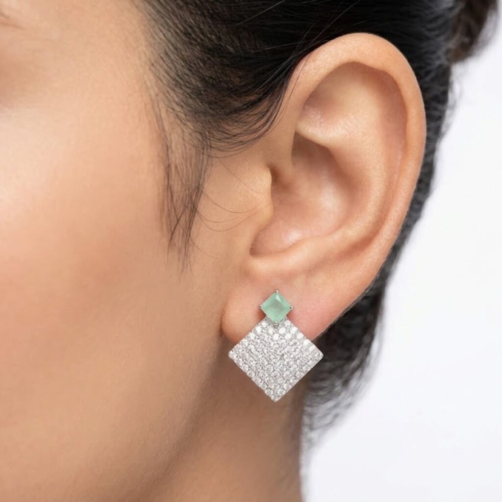 Make a statement with this Mint Stone Silver Pave Square Drop Earring. A soft mint stone stud sits above a fully crystal-covered square drop, creating a bold yet elegant contrast. Features: Silver tone finish Fully pave crystal-covered drop Mint stone stud accent Secure and comfortable backing Why You Should Buy: The mix of soft color and sparkling crystal makes this piece stand out at parties while still feeling elegant and refined. Perfect For: Parties and formal events Evening wear Special occasions