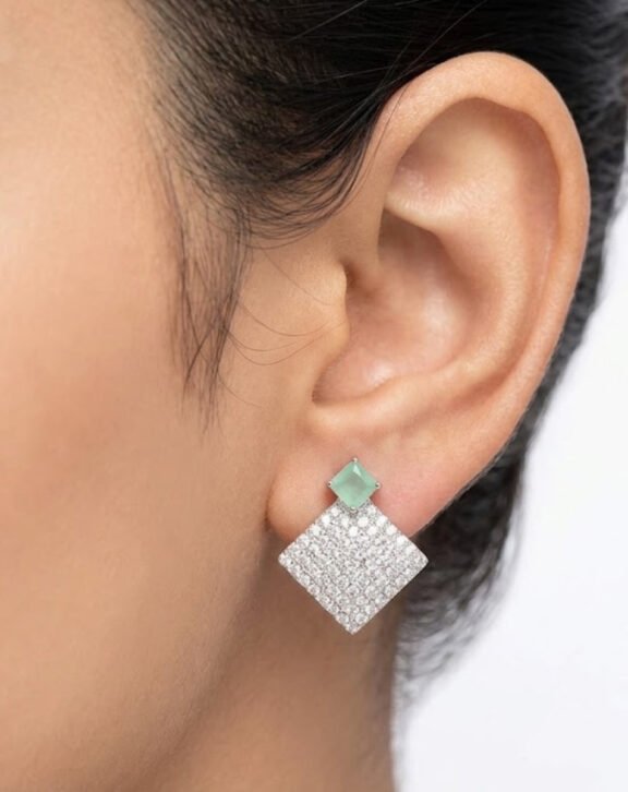 Make a statement with this Mint Stone Silver Pave Square Drop Earring. A soft mint stone stud sits above a fully crystal-covered square drop, creating a bold yet elegant contrast. Features: Silver tone finish Fully pave crystal-covered drop Mint stone stud accent Secure and comfortable backing Why You Should Buy: The mix of soft color and sparkling crystal makes this piece stand out at parties while still feeling elegant and refined. Perfect For: Parties and formal events Evening wear Special occasions