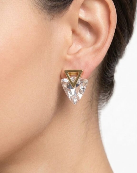 This Crystal Triangle Drop Earring features a bold faceted crystal stone in a striking triangle shape, held by a minimal gold triangle outline stud for a modern, geometric look. Features: Gold tone hardware Large clear faceted crystal Geometric triangle silhouette Statement-making design Why You Should Buy: A bold geometric design that instantly elevates a simple outfit — great for anyone who loves modern, statement jewellery. Perfect For: Statement styling Evening functions Gifting for jewellery lovers