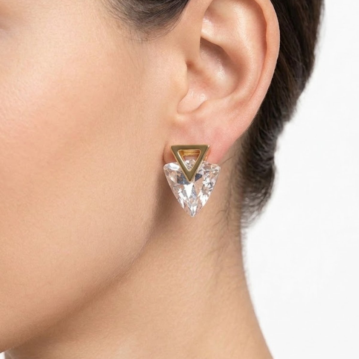 This Crystal Triangle Drop Earring features a bold faceted crystal stone in a striking triangle shape, held by a minimal gold triangle outline stud for a modern, geometric look. Features: Gold tone hardware Large clear faceted crystal Geometric triangle silhouette Statement-making design Why You Should Buy: A bold geometric design that instantly elevates a simple outfit — great for anyone who loves modern, statement jewellery. Perfect For: Statement styling Evening functions Gifting for jewellery lovers