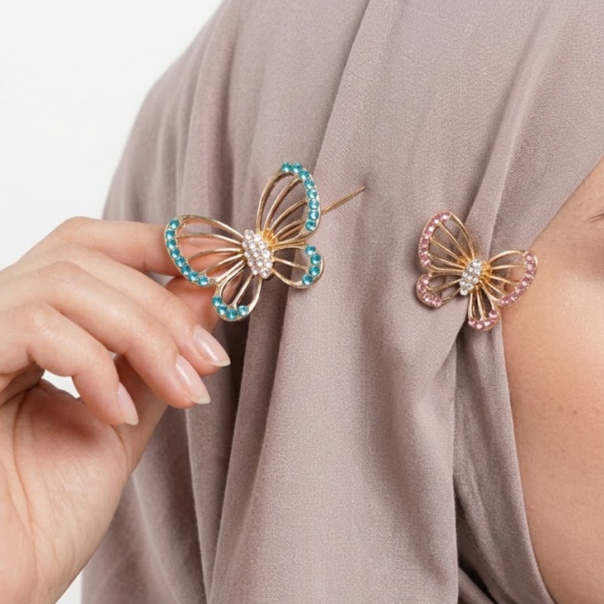 This Rhinestone Butterfly Hijab Pin Set includes two beautifully detailed butterfly pins in blue and pink tones, adding a delicate charm to your hijab or scarf styling Features: Gold-tone metal frame Rhinestone-studded wings Set of 2 (large + small) Secure pin backing Why You Should Buy: A cute and practical accessory that secures your hijab while adding a pretty sparkle — great value with two pins in one set. Perfect For: Everyday hijab styling Gifting Layered pin looks