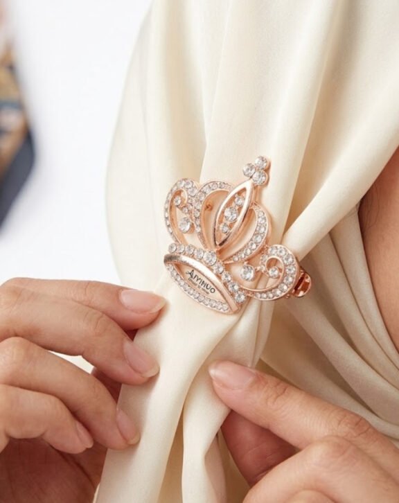 This Crystal Crown Hijab Pin features a beautifully detailed crown design fully embellished with sparkling crystals, adding a royal touch to your hijab styling. Features: Rose gold tone finish Fully crystal-embellished Sturdy pin closure Elegant crown design Why You Should Buy: A unique statement pin that instantly upgrades your hijab look for special occasions. Perfect For: Weddings and events Gifting Statement hijab styling